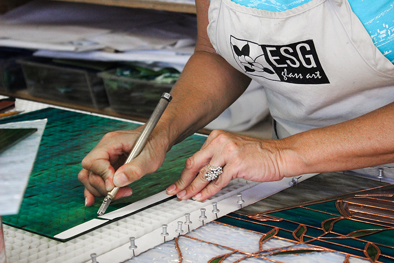 Woman cutting and shaping stained glass